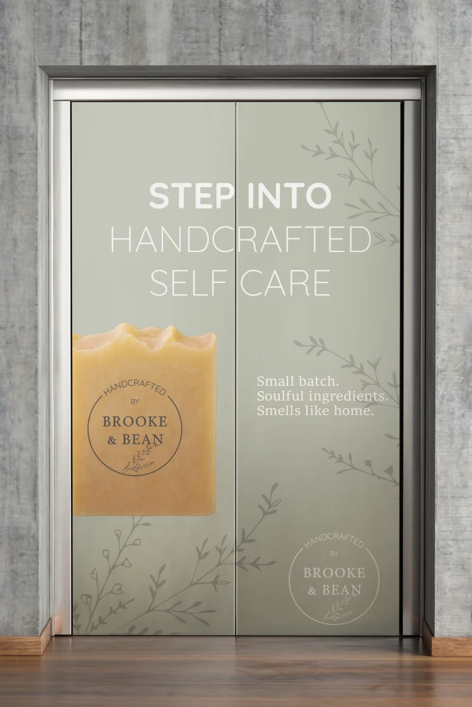 Elevator doors wrapped in custom Brooke & Bean branding, featuring elegant typography, botanical accents, and a natural soap product. A striking example of immersive brand identity and environmental design by Bean Creative Marketing.