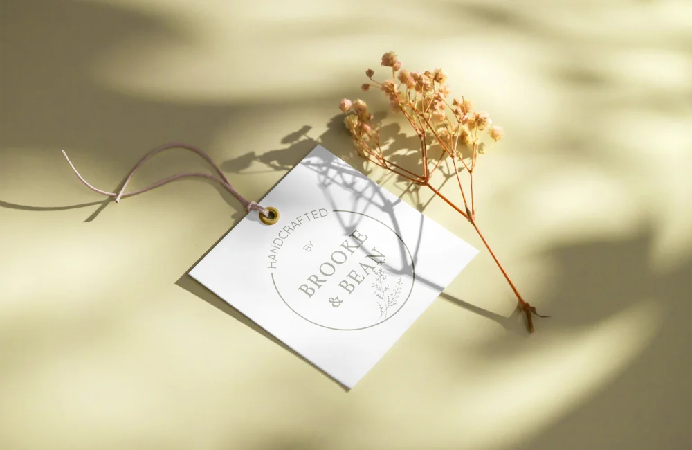 Minimalist product tag design for Brooke & Bean featuring delicate typography and botanical accents, styled with soft natural lighting and dried florals. A refined example of artisanal brand identity and tactile packaging design by Bean Creative Marketing.